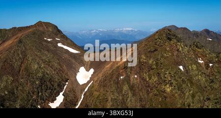 Un paysage montagneux à couper le souffle avec des pics accidentés, des parcelles de neige et un ciel bleu clair. La scène capture la beauté de la nature avec lointain Banque D'Images