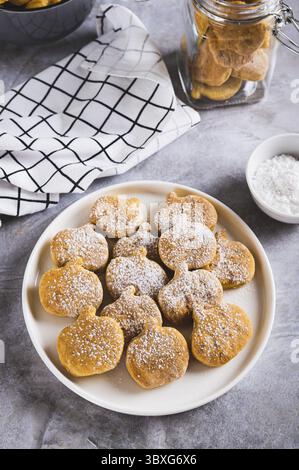 Nourriture, biscuits faits maison en forme de citrouille dans du sucre en poudre sur une assiette sur une vue verticale de table Banque D'Images