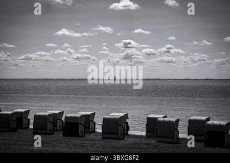 Photo en noir et blanc d'une zone côtière avec chaises longues et ciel nuageux, sur le chemin à la plage sud en 26382 Wilhelmshaven, Allemagne Banque D'Images