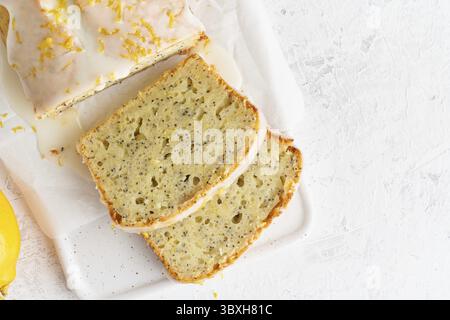 Pain au citron enrobé de glaçage sucré et saupoudré de zeste de citron. Tranche de gâteau avec agrumes, coquelicot, cuisine américaine traditionnelle. Copier l'espace, t Banque D'Images