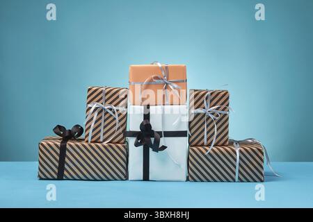 Différentes tailles, coloré, rayé et clair, marron, rose et blanc cadeaux papier attachées avec des rubans multicolores sur un tableau bleu et l'arrière-plan. Co Banque D'Images