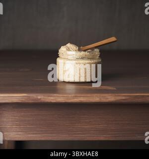 Beurre d'amande, pâte alimentaire crue faite de broyage d'amandes en beurre de noix, croquant et remuant, table en bois brun foncé, espace de copie, vue de côté Banque D'Images