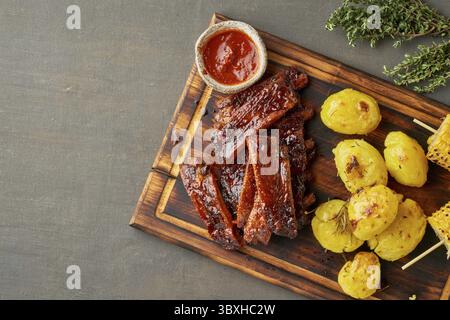 Côtes de porc grillées épicées, épis de maïs et pommes de terre écrasées. Recette de cuisson lente. Viande de porc rôtie marinée avec sauce rouge. Cuisine américaine. Haut Banque D'Images