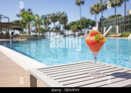 Cocktail rouge frais avec glace dans le verre sur la piscine. Jus tropical sur des vacances de luxe. Concept vacances d'été et voyages Banque D'Images