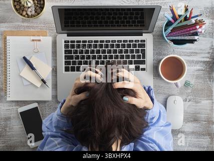 Informations excédentaires. Situation difficile, problèmes. Anxiété, stress, dépression, perte de cortrol. La femme s'est serrée la tête dans les mains. Tête de fendage par soufflage Banque D'Images