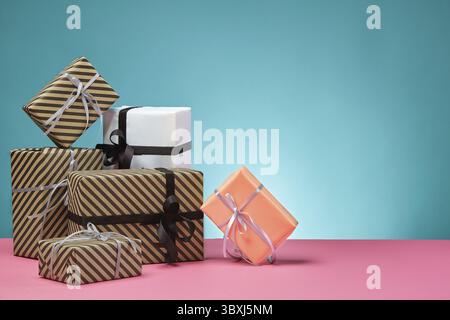 Divers, de taille moyenne, de couleur marron clair et rayé, rose et blanc, cadeaux papier attachées avec des rubans multicolores et s'incline sur une surface rose et bleu Banque D'Images