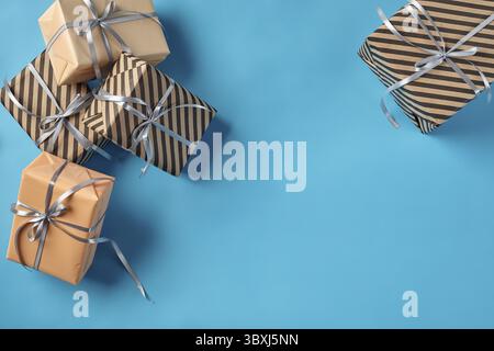 Différentes tailles, coloré, lisse et rayé marron et rose, forfaits présence papier attaché avec des rubans d'argent et d'arcs sur un fond bleu. Concept de Banque D'Images