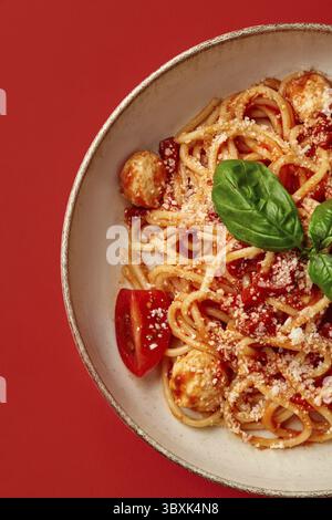 Gros plan de riches pâtes arrabbiata de style italien avec sauce tomate épicée, boulettes de viande et parmesan râpé garni de basilic aromatique frais, présenté o Banque D'Images