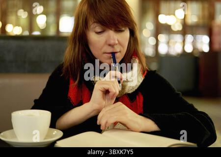 Femme dans le café écrit dans le journal, journal de balle. Slow Life, social detox, freelance, planification, auto-immersion, être un concept unique. Femme d'âge moyen Banque D'Images