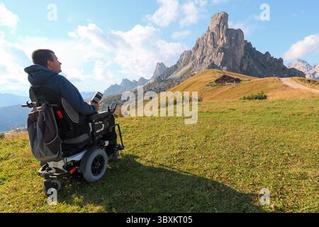 Homme handicapé en fauteuil roulant explore le paysage magnifique du col de Giau dans les Dolomites en Italie. Montagnes majestueuses et beauté naturelle dans un Banque D'Images