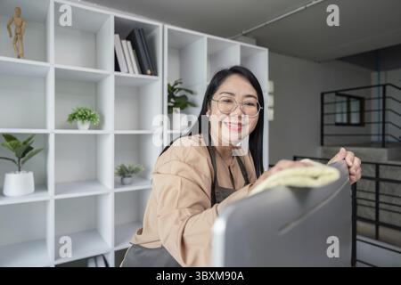 Une femme de ménage joyeuse dans une maison moderne, le nettoyage avec un chiffon. Représente les services de ménage professionnels et le nettoyage domestique Banque D'Images