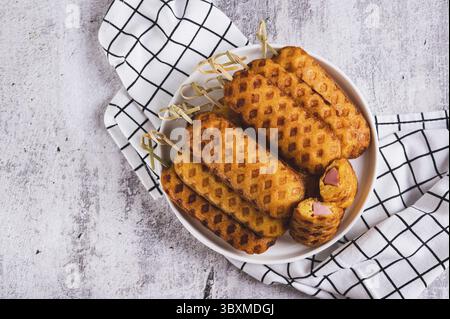 Nourriture, gros plan d'une pile de chiens de maïs maison avec saucisse sur une assiette sur une vue de dessus de table Banque D'Images