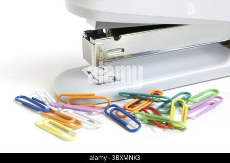 Agrafeuse et trombones multicolores sur fond blanc Banque D'Images