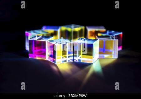 Prisme cube en cristal avec réfraction et effet holographique sur fond sombre Banque D'Images