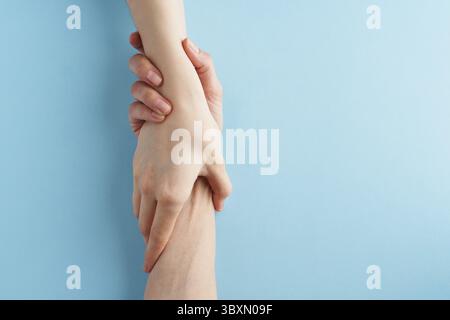 Coup de main, soutien en situation difficile, crise. Dernière chance, Hope concept. Deux mains se tenant sur fond bleu. Psychologiquement serviable Banque D'Images