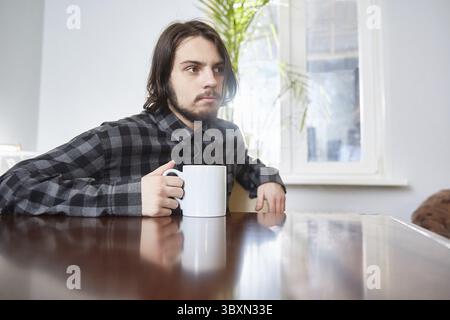 Une tasse dans les mains d'un jeune homme. Concentrez-vous sur la tasse Banque D'Images