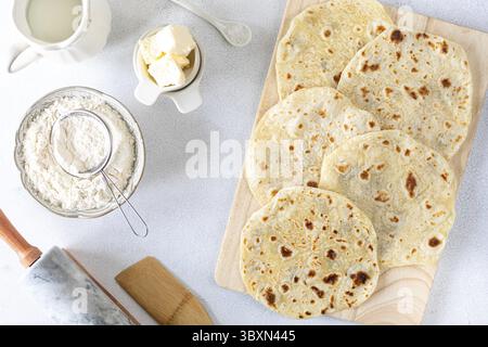 Nourriture, tortillas de blé maison, pain pita, tortilla, pita avec des ingrédients pour cuisiner sur une table blanche. Vue de dessus Banque D'Images