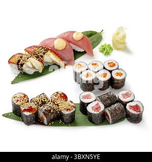 Ensemble de sushis frais avec nigiri, maki et uramaki servis sur des feuilles de bambou, avec wasabi et gingembre, créant une cuisine japonaise visuellement attrayante ex Banque D'Images