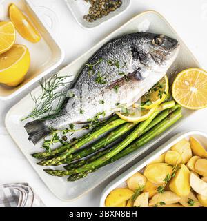 Nourriture, Dorado crue fraîche avec des épices d'asperges, des herbes, du citron et du sel sur fond blanc Banque D'Images