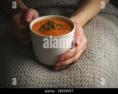 Soupe à la crème Pupmkin dans les mains, déjeuner végétarien diététique. Vue latérale. Photo sombre Banque D'Images