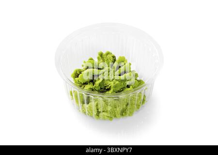 Pâte de wasabi verte servie dans un petit récipient en plastique, prête à accompagner les sushis ou autres plats japonais Banque D'Images