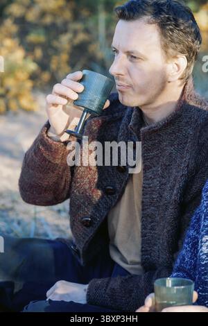 Portrait masculin. Beau jeune homme avec de longs cheveux foncés sur une journée d'automne ensoleillée à l'extérieur. Photo verticale. Banque D'Images