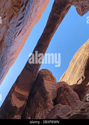 Dans un canyon de fente, sur le Fiery Furnace Trail, dans le parc national d'Arches, regardant vers le haut des formations d'arche et des parois du canyon un jour d'été avec clair, bleu Banque D'Images