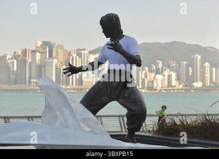 25 novembre 2021, HONG KONG, CHINE : le voile de soie tombe alors que le nouveau visage de la statue de Bruce Lee apparaît devant le public à Hong Kong sur le front de mer du port de Victoria. Pour commémorer le 81e anniversaire du légendaire Kung Fu Super Star de Hong Kong, la statue en bronze réarrangée de feu BRUCE LEE est dévoilée cet après-midi à Avenue of Stars à Hong Kong. La statue en bronze nouvellement façonnée est exposée avec Bruce Lee portant un haut blanc emblématique et la ceinture noire qu'il portait dans le film BIG BOSS.Nov-25,2021Hong Kong.ZUMA/Liau Chung-Ren (crédit image : © Liau Chung-Ren/ZUMA Press Wire) Banque D'Images