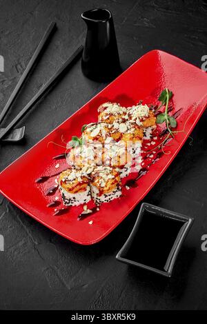 Délicieux rouleaux de sushi garni de fromage poêlé brun doré et de chapeaux de fruits de mer saupoudrés de sésame et de parmesan râpé, garnis de légumes verts servis Banque D'Images