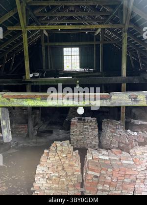 Fagervik : vue intérieure d'une ancienne grange avec poutres en bois et pieux de briques, atmosphère rustique, lumière douce à travers la fenêtre. Banque D'Images