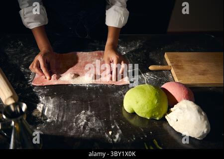 Un chef prépare habilement des raviolis faits maison à l'aide de pâtes aux couleurs vives, symbolisant la créativité culinaire et la riche tradition italienne Banque D'Images