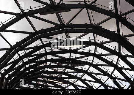 Modèle moderne de structure en acier. Construction métallique courbée avec verre. Conception architecturale abstraite de cadre de toit. Géométrie d'arrière-plan industrielle. Banque D'Images