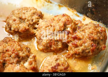 Pâtés de viande faits maison dans un plateau de four. Côtelettes de viande hachée cuites juteuses aux herbes. Galettes de bœuf ou de porc cuites dans leur propre jus. Banque D'Images