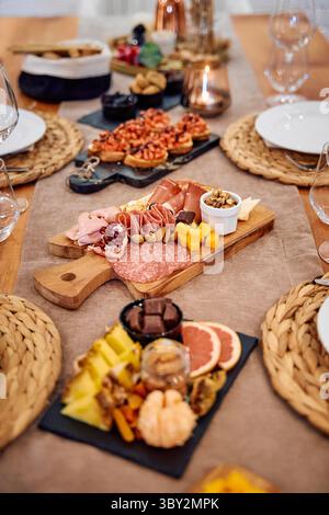 Une planche de charcuterie magnifiquement agencée présentant une variété de viandes, fromages, fruits et noix. présenté sur des plateaux en bois et en ardoise, parfait pour Banque D'Images