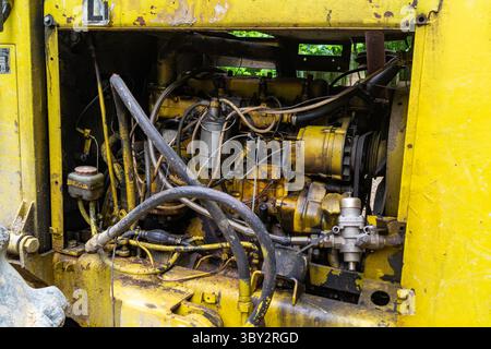 Vieux moteur jaune et rouillé avec fils et flexibles à l'intérieur du compartiment machine rouillée Banque D'Images