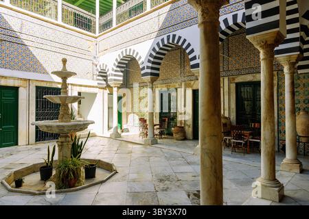 Cour décorée de carreaux, fontaines et arcades colorées à colonnes dans le palais historique de Dar Bach Hamba dans la médina de Tunis, Tunisie Banque D'Images
