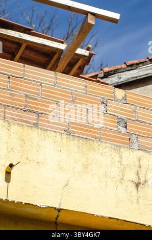 Mur de briques inachevé sur un chantier de construction de maison. Travaux en cours sur une extension de bâtiment résidentiel. Banque D'Images