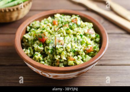 Salade orientale Tabbouleh dans un bol en céramique sur une table en bois. Concept de cuisine traditionnelle libanaise ou syrienne. Plat végétarien ou végétalien. style rustique Banque D'Images