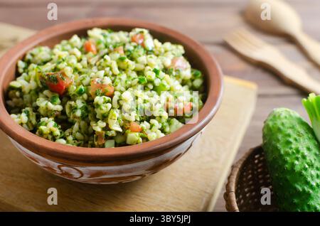 Salade orientale Tabbouleh dans un bol en céramique sur une table en bois. Concept de cuisine traditionnelle libanaise ou syrienne. Plat végétarien ou végétalien. style rustique Banque D'Images