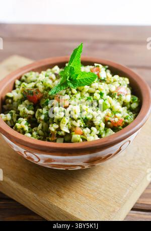 Salade orientale Tabbouleh dans un bol en céramique sur une table en bois. Concept de cuisine traditionnelle libanaise ou syrienne. Plat végétarien ou végétalien. style rustique Banque D'Images