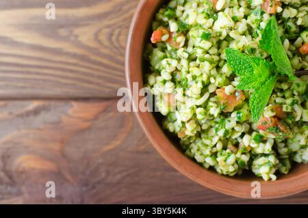 Salade orientale Tabbouleh dans un bol en céramique sur une table en bois. Concept de cuisine traditionnelle libanaise ou syrienne. Plat végétarien ou végétalien. Sélect. F Banque D'Images