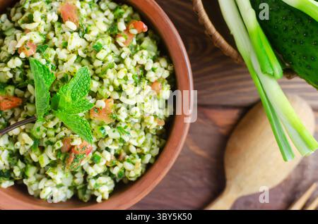 Salade orientale Tabbouleh dans un bol en céramique sur une table en bois. Concept de cuisine traditionnelle libanaise ou syrienne. Plat végétarien ou végétalien. Sélect. F Banque D'Images
