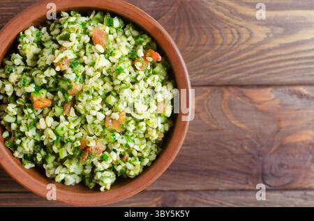 Salade orientale Tabbouleh dans un bol en céramique sur une table en bois. Concept de cuisine traditionnelle libanaise ou syrienne. Plat végétarien ou végétalien. Sélect. F Banque D'Images