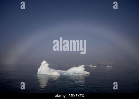 Un arc de brouillard s'étend sur un iceberg dans le Vikingebugt, dans l'Arctique du Groenland, en Europe Banque D'Images