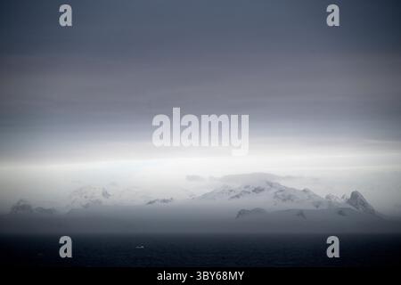Le soleil levant peint un paysage pastel de nuages et de montagnes quelque part dans le détroit de l'Antarctique, à la pointe nord de la péninsule Antarctique, Ant Banque D'Images