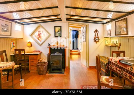 Intérieur confortable d'une péniche traditionnelle à Amsterdam avec poêle à bois, meubles vintage et charme nautique, mettant en valeur la vie du canal hollandais. Banque D'Images