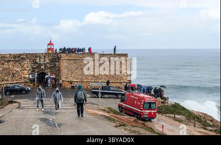Nazare, Portugal, 9 mars 2025. Les visiteurs se sont rassemblés près du phare de Nazaré (Farol da Nazaré) pour observer les vagues et les surfeurs par temps pluvieux. Banque D'Images