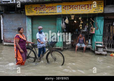 26 juin 2021, Kolkata, Bengale occidental, Inde : une dame aide un homme à marcher à vélo dans une rue inondée de Kolkata , Inde , le 26 juin 2021 . La marée haute sur le Gange a provoqué des inondations massives dans diverses parties des zones de basse altitude sur la rive du Gange à Kolkata (crédit image : © Debarchan Chatterjee/ZUMA Press Wire) Banque D'Images