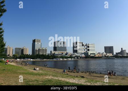 Vie quotidienne au Japon les gens se détendent sur la plage de sable artificiel du parc balnéaire d'Odaiba, avec une vue panoramique sur le paysage urbain d'Odaiba Banque D'Images