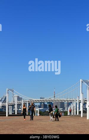 Vie quotidienne au Japon Odaiba Promenade avec vue sur la Tour de Tokyo et le pont arc-en-ciel de Tokyo, avec les touristes qui vont et viennent Banque D'Images